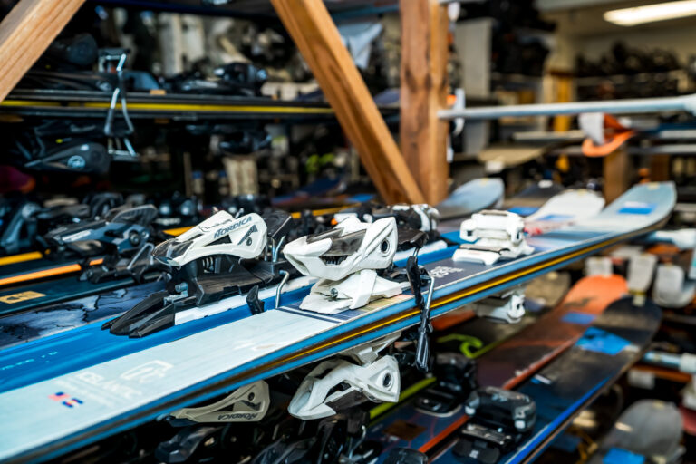 Variety of skis on wooden rack.