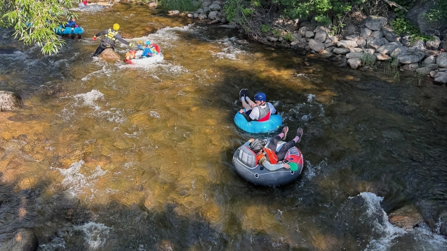 Multiple inner-tube riders float down a rocky creek